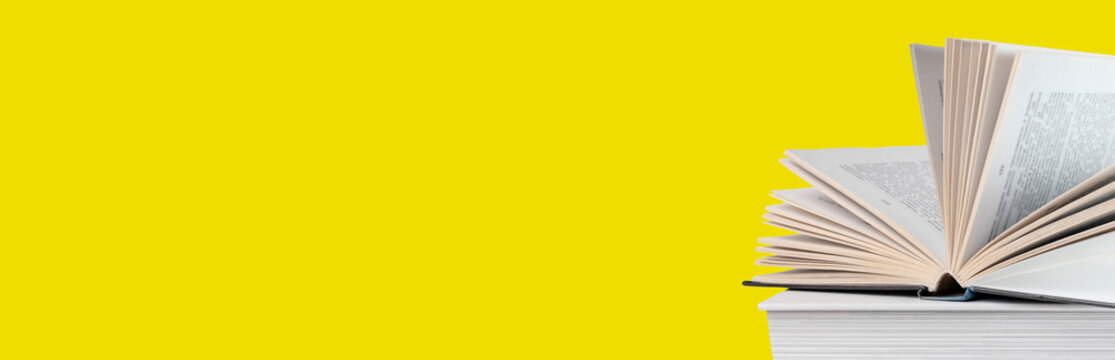 Banner with open book lying at books stack on yellow background. Reading and turning pages. Education and getting knowledge concept. High quality photo
