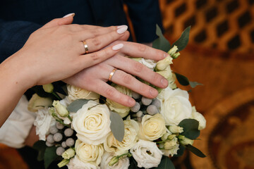 Obraz na płótnie Canvas Two gold wedding rings on a finger and a wedding bouquet of roses