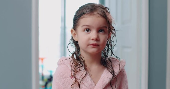 Cute toddler girl posing in pink robe after a bath. 4K footage.