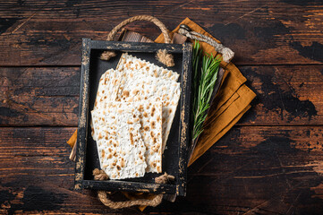 Passover matzos of celebration with matzo unleavened bread in a wooden tray with herbs. Wooden...