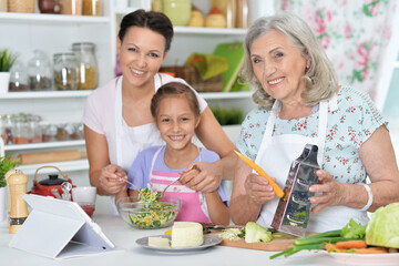 Portrait of happy family coocking salad in  kitchen