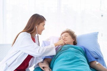 Fototapeta premium A young beautiful doctor is checking an old patient woman.