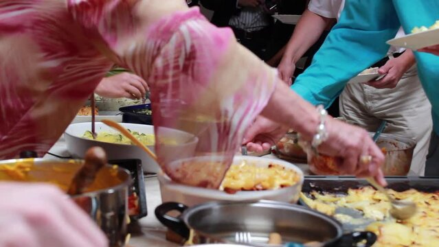 Pople helping themselves at a potluck table with plenty of food in self-service mode