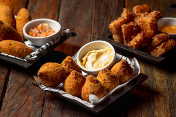 Porções de aperitivo de bar, coxinha, dadinho de tapioca e bolinho de carne.