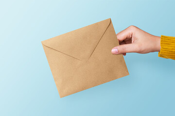 Hand holding blank brown envelope on blue background. Business and finance concept