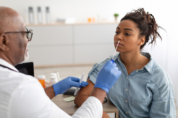 Fototapeta premium Doctor taking PCR test sample from potentially infected black woman
