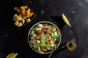 Caesar salad with chicken in a plate on a dark background