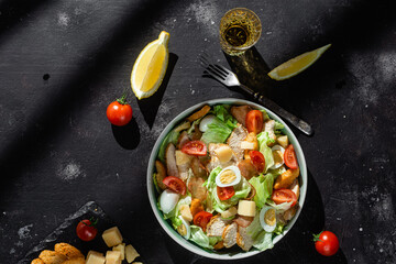 Caesar salad with chicken in a plate on a dark background