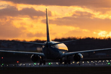 Fototapeta na wymiar Aircraft ready for take off at Stuttgart Airport, against golden sunset sky with some clouds, partly blurred by heat of jet engines 