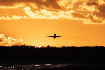 Fototapeta na wymiar Aircraft taking off at Stuttgart Airport, against golden sunset sky with some clouds 
