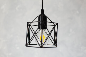 Close-up of black hanging lamp on grey background.