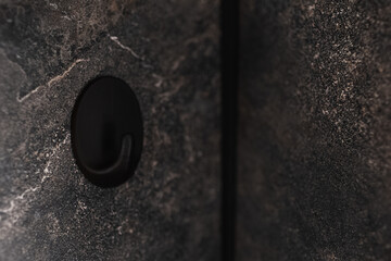 Close-up of clothes hook on background marble wall.
