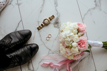 A bridal bouquet of white and pink roses, wedding rings, men's watches and the groom's shoes. wedding details 