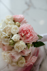 Delicate wedding bouquet of pink and white roses and wedding rings on it 