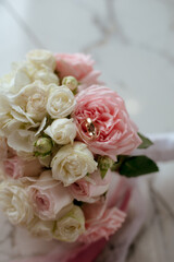 Delicate wedding bouquet of pink and white roses and wedding rings on it 