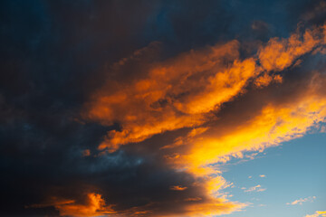Fototapeta na wymiar Yellow sunlight of sunset falls on dark cloudy sky.