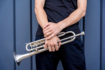 Young street musician playing the trumpet near the big blue wall