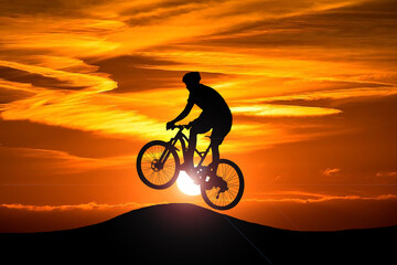 Fototapeta na wymiar An action cyclist silhouette with the setting sun in the background. Action and adventure sports concept.