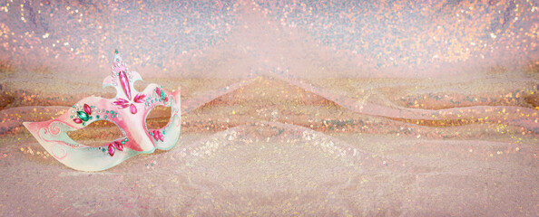 Photo of elegant and delicate Venetian mask over pink sequins chiffon sparkle background. banner