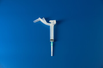 Syringe with needle lies on blue background 