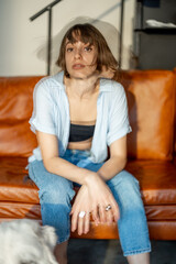 Fototapeta premium Portrait of a young confident woman sitting on couch at home. Double exposure image technic