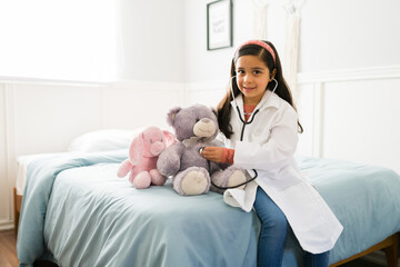 Child playing with a stethoscope and a teddy bear