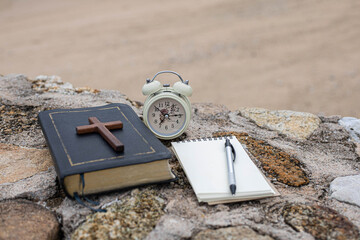 Alarm clock and the Bible on the rock prepare for Bible study.