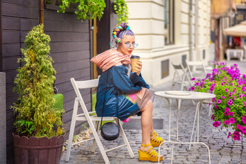 Cool gen z girl with piercing and crazy hair enjoy takeaway coffee on street cafe