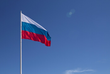 Waving Russian flag against a blue sky with clouds and empty space for text. Room for text. National flag of the Russian Federation.