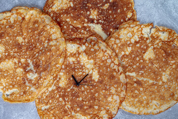 Russian pancake with clock hands as a symbol of the time of the Maslenitsa holiday
