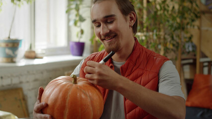 A young man is drawing neatly on the pumpkin