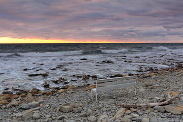 landscape the sea at sunset a bench on a rocky shore