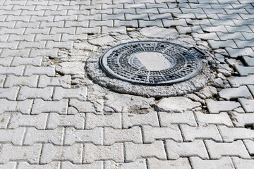 manhole cover, iron manhole cover, in the middle of the stone paved road,