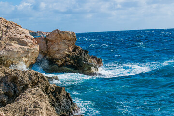 Fototapeta na wymiar Sea waves splashing against the rocks at Għar Lapsi