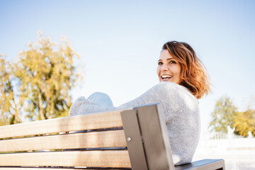 Joyful carefree woman laughing as she relaxes outdoors - obrazy, fototapety, plakaty