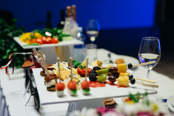 A white ceramic coaster with hors d'oeuvres on the wedding table..Appetizers on plates. Catering service. Wedding welcome food.