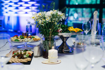A festively served table inside the restaurant. A candle on the table. Wedding banquet.