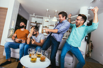 Smiling male friends with gamepads and beer playing video game at home © Mediteraneo