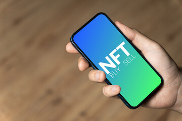 NFT buy or sell  - hand holding a phone