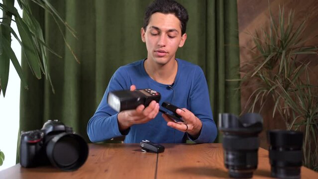Video tutorial on how to work with radio synchronizers for photo flash. A young attractive Arab man is filming himself on camera. Online tutor, mentor.