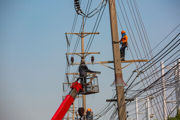 The male worker crane cable car repairs the electric pole and growing