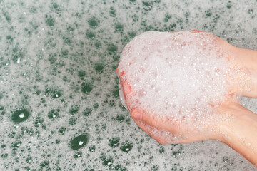 Hands with white soap foam on the background of water with foam.
