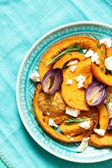Roasted pumpkin,onion and garlic with thyme and rosemary on turquoise blue background. Rustic food photography.  Close-up. Top view with copy space.