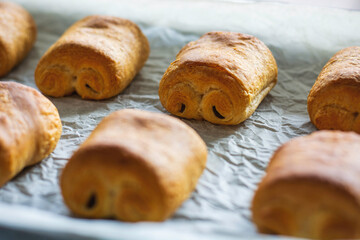Close up freshly baked chocolate croissants on tray. Traditional french pastry.