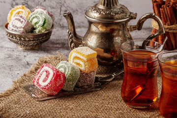 Traditional Turkish delight with Turkish tea on gray background. Ramadan Kareem celebration concept. Fragrant Turkish tea and Turkish sweets in national dishes.