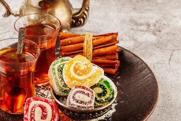 Traditional Turkish delight with Turkish tea on gray background. Ramadan Kareem celebration concept. Fragrant Turkish tea and Turkish sweets in national dishes.