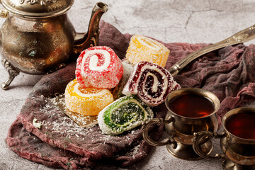 Traditional Turkish delight with Turkish tea on gray background. Ramadan Kareem celebration concept. Fragrant Turkish tea and Turkish sweets in national dishes.