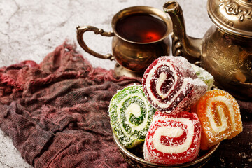 Traditional Turkish delight with Turkish tea on gray background. Ramadan Kareem celebration concept. Fragrant Turkish tea and Turkish sweets in national dishes.