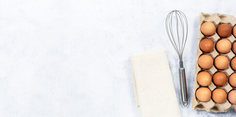 Chicken Eggs and Egg Beaters,Top view carton box eggs, egg yolk, whisk, Eggshell on a wooden background.