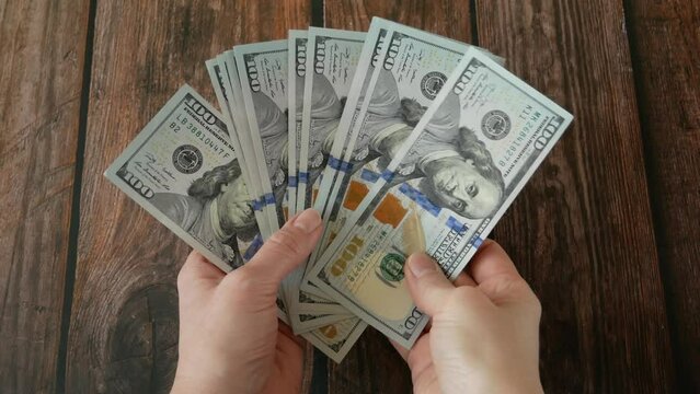 hand holding big stack of dollar money on wooden background. money cash, wealth symbol, loan money